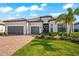 Charming single-story home featuring a tile roof, a brick paver driveway, and a two-car garage at 17916 Northwood Pl, Lakewood Ranch, FL 34202