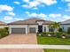 Charming single-story home with a tile roof, three-car garage, and vibrant landscaping, creating a welcoming entrance at 17916 Northwood Pl, Lakewood Ranch, FL 34202