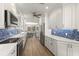 Modern kitchen features stainless steel appliances, white cabinets, and blue tile backsplash at 1928 Harbourside Dr # 1403, Longboat Key, FL 34228