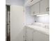 Bright laundry room with white cabinets, a folding shelf, and a modern washer and dryer set at 1928 Harbourside Dr # 1403, Longboat Key, FL 34228
