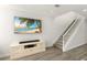 Cozy living room with a large TV, beige entertainment center, light wood flooring, and stairs at 1928 Harbourside Dr # 1403, Longboat Key, FL 34228