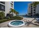 Outdoor hot tub and sparkling pool surrounded by lush tropical landscaping and modern building at 1928 Harbourside Dr # 1403, Longboat Key, FL 34228