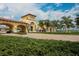 Community entrance featuring stucco buildings, arched walkways, brick drive, and well-manicured landscaping at 19993 Benissimo Dr, Venice, FL 34293