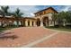Elegant community entrance with brick driveways, manicured landscaping, stucco buildings and arched entrances at 19993 Benissimo Dr, Venice, FL 34293