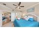 A calm main bedroom featuring a ceiling fan, open doorway, and beautiful blue bedding at 19993 Benissimo Dr, Venice, FL 34293
