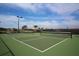 Community tennis court with green surface, black fencing, and clear blue skies at 19993 Benissimo Dr, Venice, FL 34293