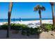 Beautiful white sand beach with blue umbrellas, lounge chairs, and clear blue water, perfect for relaxation and recreation at 2100 Benjamin Franklin Dr # 104, Sarasota, FL 34236