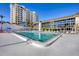 Beautiful community pool surrounded by lounge chairs and palm trees with large building at 2100 Benjamin Franklin Dr # 104, Sarasota, FL 34236