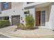 Modern townhome exterior boasts a garage, sleek front door, and vibrant plants, enhancing curb appeal at 232 Cosmopolitan Ct, Sarasota, FL 34236