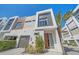Contemporary exterior features a garage, stylish front door, complemented by manicured greenery and a palm tree at 232 Cosmopolitan Ct, Sarasota, FL 34236