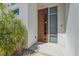 Elegant wood front door is surrounded by verdant tropical foliage, offering a welcoming entrance at 232 Cosmopolitan Ct, Sarasota, FL 34236