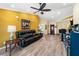 Living room with sleek wood floors, yellow walls, a dark leather sofa, and access to the kitchen at 3865 N Cranberry Blvd, North Port, FL 34286