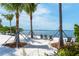 Picturesque beach with a hammock, lounge chairs, and tranquil water views framed by palm trees at 388 Aruba Cir # 201, Bradenton, FL 34209