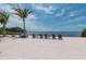 Secluded beach featuring lounge chairs, palm trees, and calming waterfront scenery at 388 Aruba Cir # 201, Bradenton, FL 34209