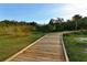 Scenic wooden boardwalk winding through a lush green landscape with a clear blue sky above, great for walks and nature appreciation at 388 Aruba Cir # 201, Bradenton, FL 34209