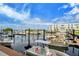 A view of a marina with pontoon boats and yachts docked, with modern buildings and a clear sky in the background at 388 Aruba Cir # 201, Bradenton, FL 34209