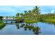 Scenic pond featuring a wooden bridge, palm trees, and reflections of the surrounding landscape under a cloudy sky at 388 Aruba Cir # 201, Bradenton, FL 34209