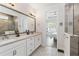 Bathroom with dual sinks, a framed mirror, and glass-enclosed shower at 3926 Sunshine Pine Ave, Bradenton, FL 34203