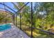 The screened pool area features brick pavers, screened walls, and views of a wooded area at 4015 Celestial Blue Ct, Bradenton, FL 34211