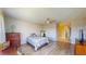 Large bedroom with light walls and laminate floors, with a ceiling fan, dresser, desk, and hallway access at 4201 Center Gate Ln # 1, Sarasota, FL 34233