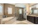 Stylish bathroom featuring a soaking tub, a glass-enclosed shower, and vanity areas at 551 Ranger Ln, Longboat Key, FL 34228