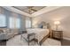 Serene main bedroom with a plush bed, sitting area, wood floors, and tray ceiling at 551 Ranger Ln, Longboat Key, FL 34228