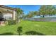 Spacious backyard with lush green grass, tall trees, and a glimpse of the home's architecture and patio at 5723 Title Row Dr, Bradenton, FL 34210