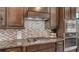Close up of the cooktop with mosaic backsplash and granite countertops at 5723 Title Row Dr, Bradenton, FL 34210