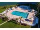Aerial view of a community pool with lounge chairs, a hot tub, and lush landscaping near the ocean at 6269 Palma Del Mar S Blvd # 308, St Petersburg, FL 33715
