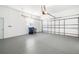 A spacious garage featuring a ceiling fan, garage door, and epoxy floors at 664 Silk Oak Dr, Venice, FL 34293