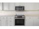 Modern kitchen features white cabinets, stainless steel appliances, and ample counter space at 664 Silk Oak Dr, Venice, FL 34293