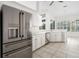 Bright eat-in kitchen features stainless steel refrigerator, white cabinets, and tile flooring at 664 Silk Oak Dr, Venice, FL 34293