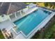 Aerial view captures a large swimming pool next to a covered area and lounge seating at 664 Silk Oak Dr, Venice, FL 34293