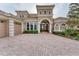 Elegant front exterior with a paver driveway, three-car garage, and arched entryway at 6822 Dominion Ln, Lakewood Ranch, FL 34202