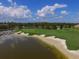 A beautiful lakefront golf course features lush greens, a sandy beach, and well-manicured landscaping at 6822 Dominion Ln, Lakewood Ranch, FL 34202