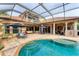 In-ground pool and hot tub surrounded by a screen with outdoor kitchen and dining area at 6822 Dominion Ln, Lakewood Ranch, FL 34202