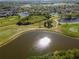 Aerial view of a golf course with a shimmering lake surrounded by lush greenery and residential homes in the distance at 711 Planters Manor Way, Bradenton, FL 34212