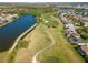 Aerial view of a golf course with homes nearby a pond and a manicured path, highlighting a community amenity at 711 Planters Manor Way, Bradenton, FL 34212