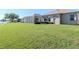 View of the back yard with a screened-in lanai overlooking the green lawn and a lake at 711 Planters Manor Way, Bradenton, FL 34212