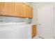 Bright laundry room featuring wooden cabinets above washer and dryer, plus a utility sink and door at 711 Planters Manor Way, Bradenton, FL 34212