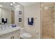Tidy bathroom with a marble vanity, a glass shower, and ocean-themed artwork, with blue towels accenting it at 755 S Palm Avenue # 604, Sarasota, FL 34236