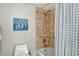 Tile-surround shower and tub combination featuring safety bar, mounted shower head, and framed art at 755 S Palm Avenue # 604, Sarasota, FL 34236