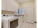 Bright laundry room featuring white cabinets, granite counters, modern washer, and dryer at 7847 Chick Evans Pl, Sarasota, FL 34240
