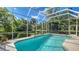 Inviting screened-in pool surrounded by lush landscaping and clear blue skies at 7847 Chick Evans Pl, Sarasota, FL 34240