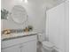 Bright bathroom with a white vanity, granite countertop, round mirror, and a shower with a white curtain at 8016 Grande Shores Dr, Sarasota, FL 34240