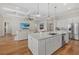 Open-concept kitchen with white cabinets, stainless steel appliances, and a large island, flowing into the living area at 8016 Grande Shores Dr, Sarasota, FL 34240