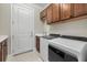 Laundry room with wooden cabinets, tile flooring, a utility sink, and a modern washer and dryer at 8016 Grande Shores Dr, Sarasota, FL 34240