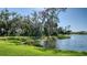 Lakeside backyard oasis with lush green grass and mature trees for privacy and a scenic view at 8918 Waxwing Way, Parrish, FL 34219