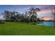 Picturesque backyard view featuring a serene lake surrounded by lush greenery at sunset at 8918 Waxwing Way, Parrish, FL 34219