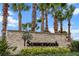 A stone sign for Summerwoods with stacked stone and black lettering sits among lush green landscaping with palm trees at 8918 Waxwing Way, Parrish, FL 34219